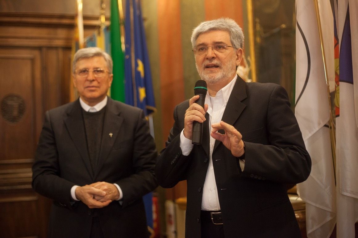 Due uomini sono in piedi uno accanto all'altro e uno tiene in mano un microfono.