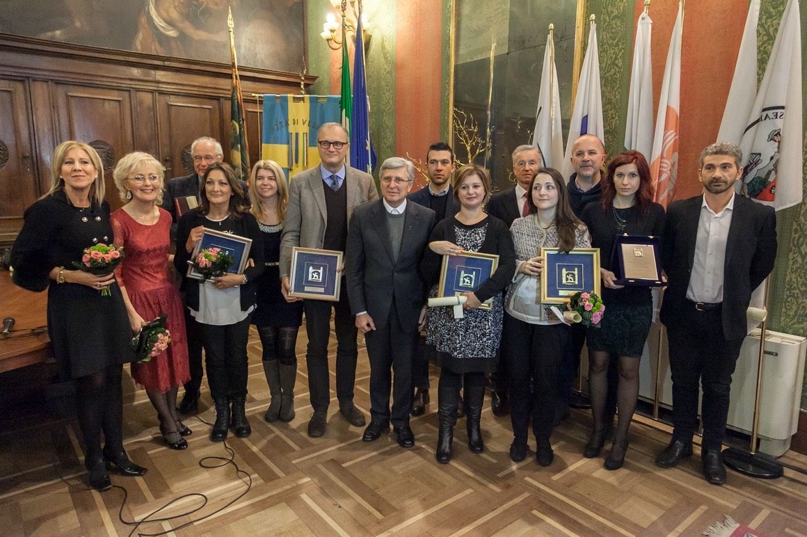 Un gruppo di persone posa per una foto in una stanza con le bandiere.