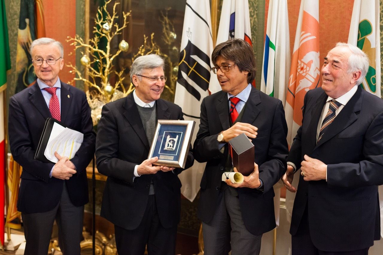 Un gruppo di uomini in giacca e cravatta sta in piedi davanti alle bandiere