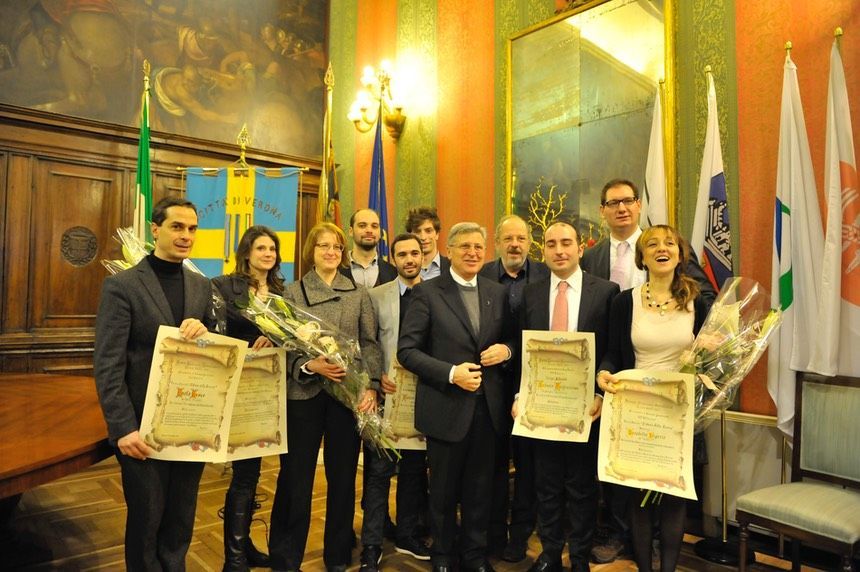 Un gruppo di persone in piedi in una stanza con in mano dei certificati