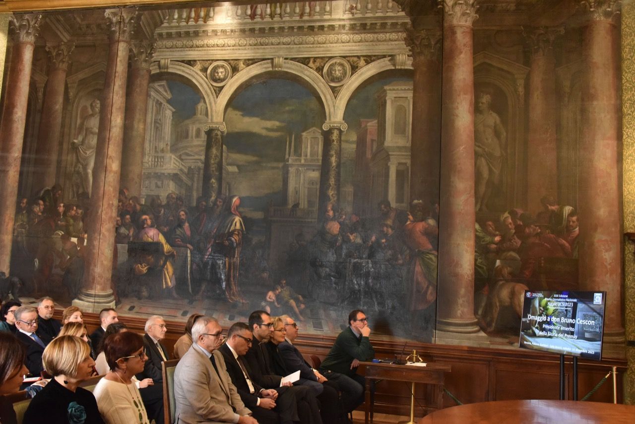 Un gruppo di persone è seduto davanti ad un grande dipinto.