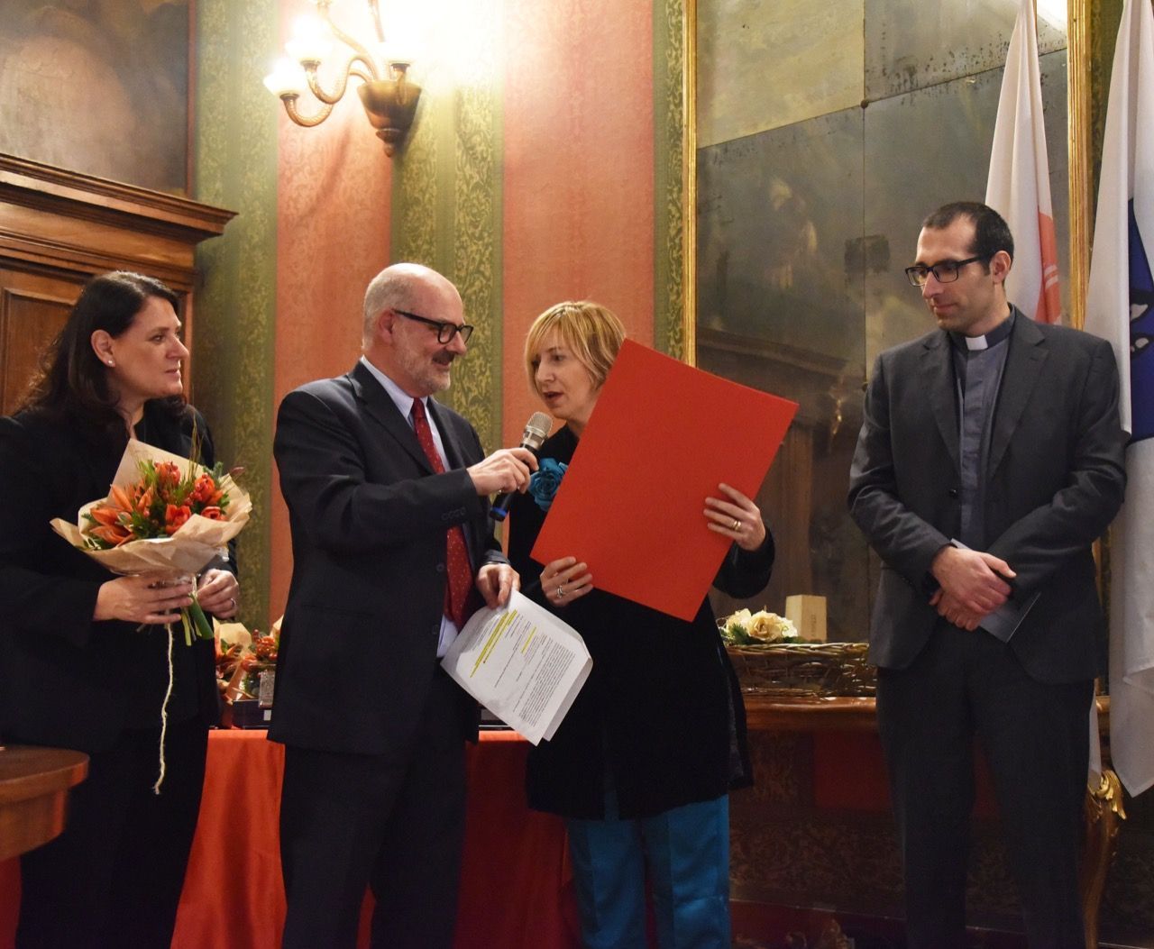 Un gruppo di persone in piedi attorno a una donna che tiene in mano un pezzo di carta rosso