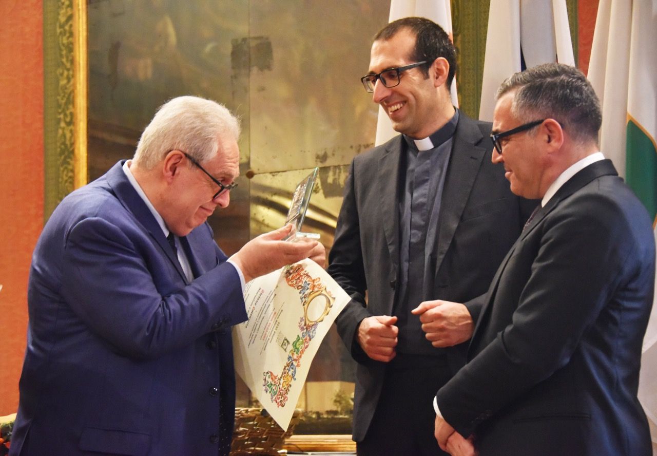 Un uomo in giacca e cravatta sta consegnando un certificato a un altro uomo in giacca e cravatta.