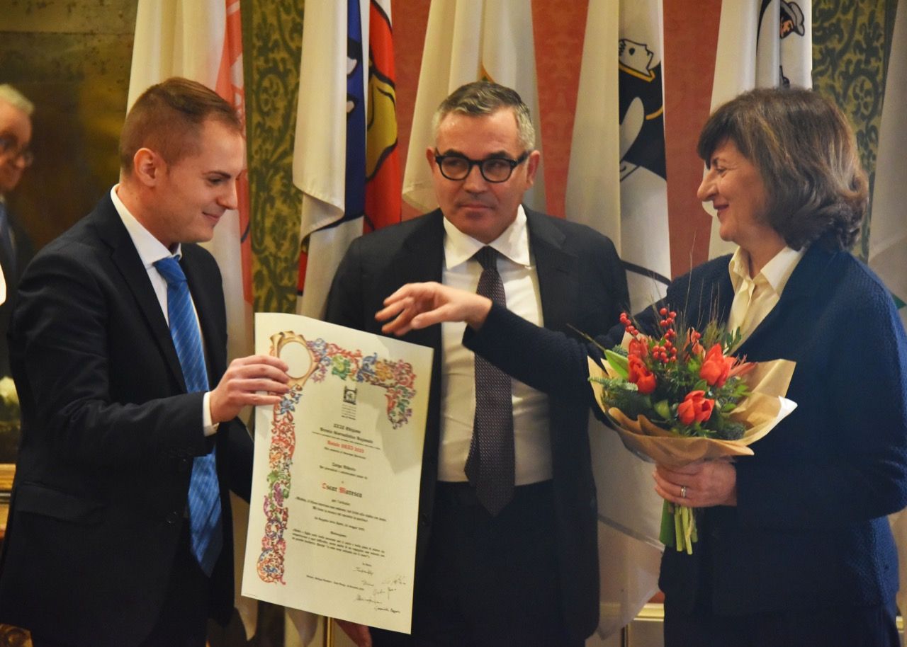 Una donna tiene in mano un mazzo di fiori e un uomo tiene in mano un certificato