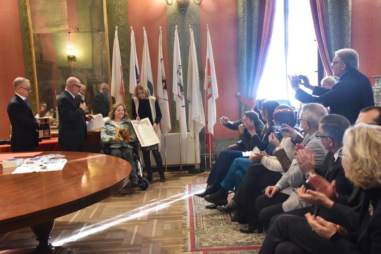 Un gruppo di persone è seduto attorno a un tavolo in una stanza con le bandiere.