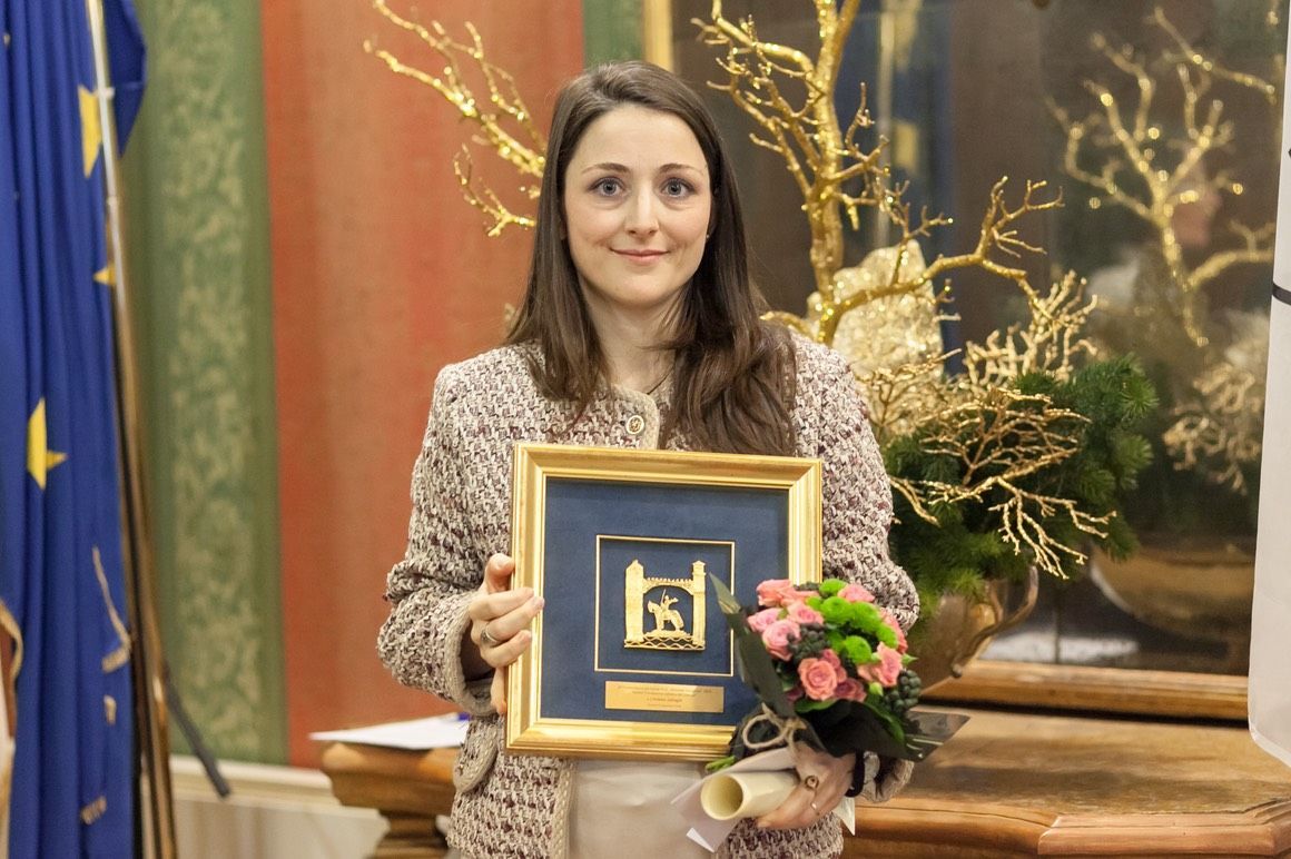 Una donna tiene in mano un quadro incorniciato e un mazzo di fiori.