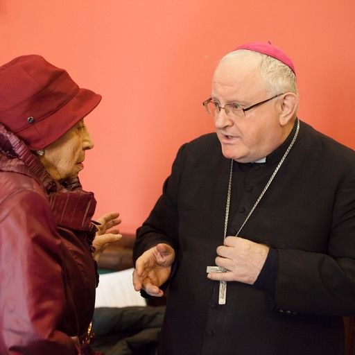 Un uomo con gli occhiali e un cappello viola sta parlando con una donna