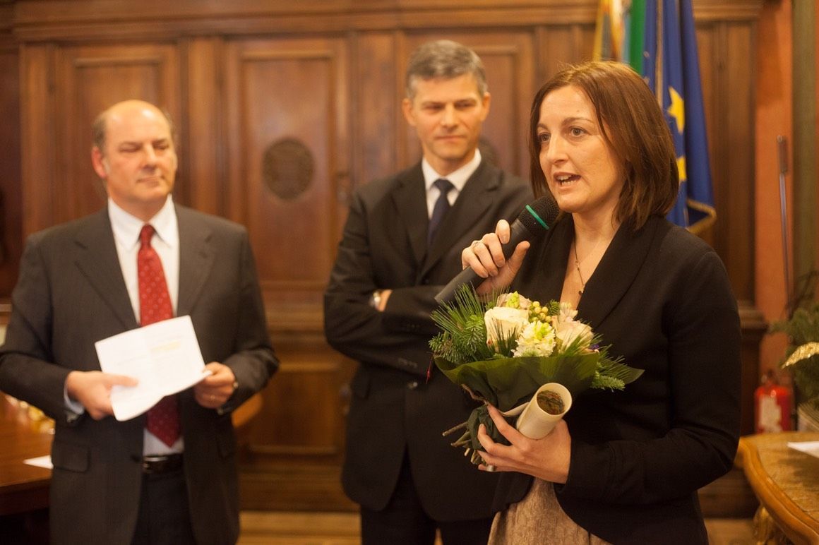 Una donna tiene in mano un mazzo di fiori e parla al microfono