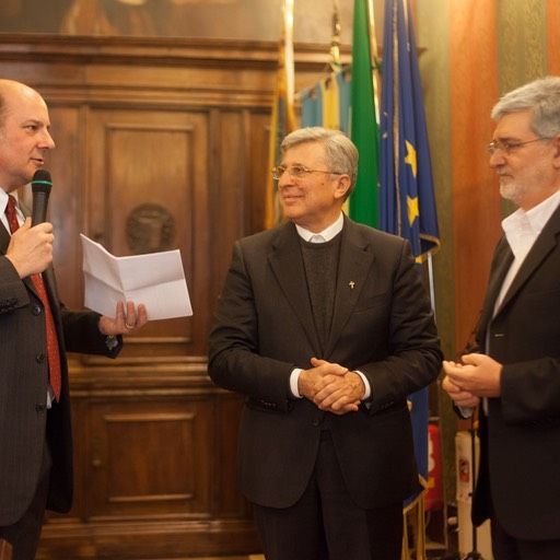 Un uomo in giacca e cravatta tiene in mano un pezzo di carta e parla al microfono