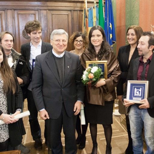 Un gruppo di persone in posa per una foto con una donna che tiene in mano un mazzo di fiori