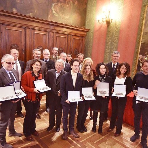 Un gruppo di persone in piedi in una stanza con in mano dei certificati