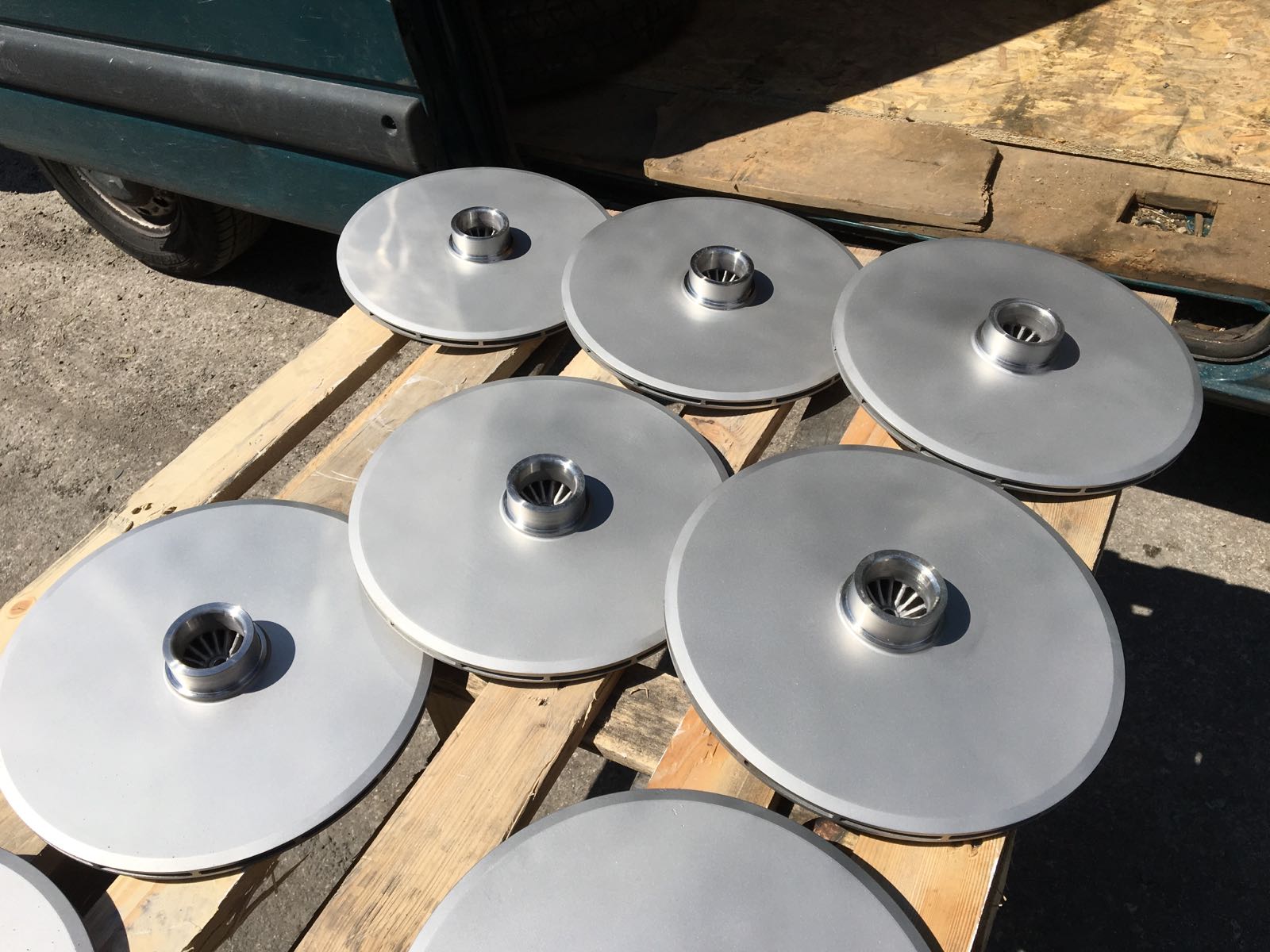 Un mucchio di dischi di metallo con sopra dei dadi su un pallet di legno