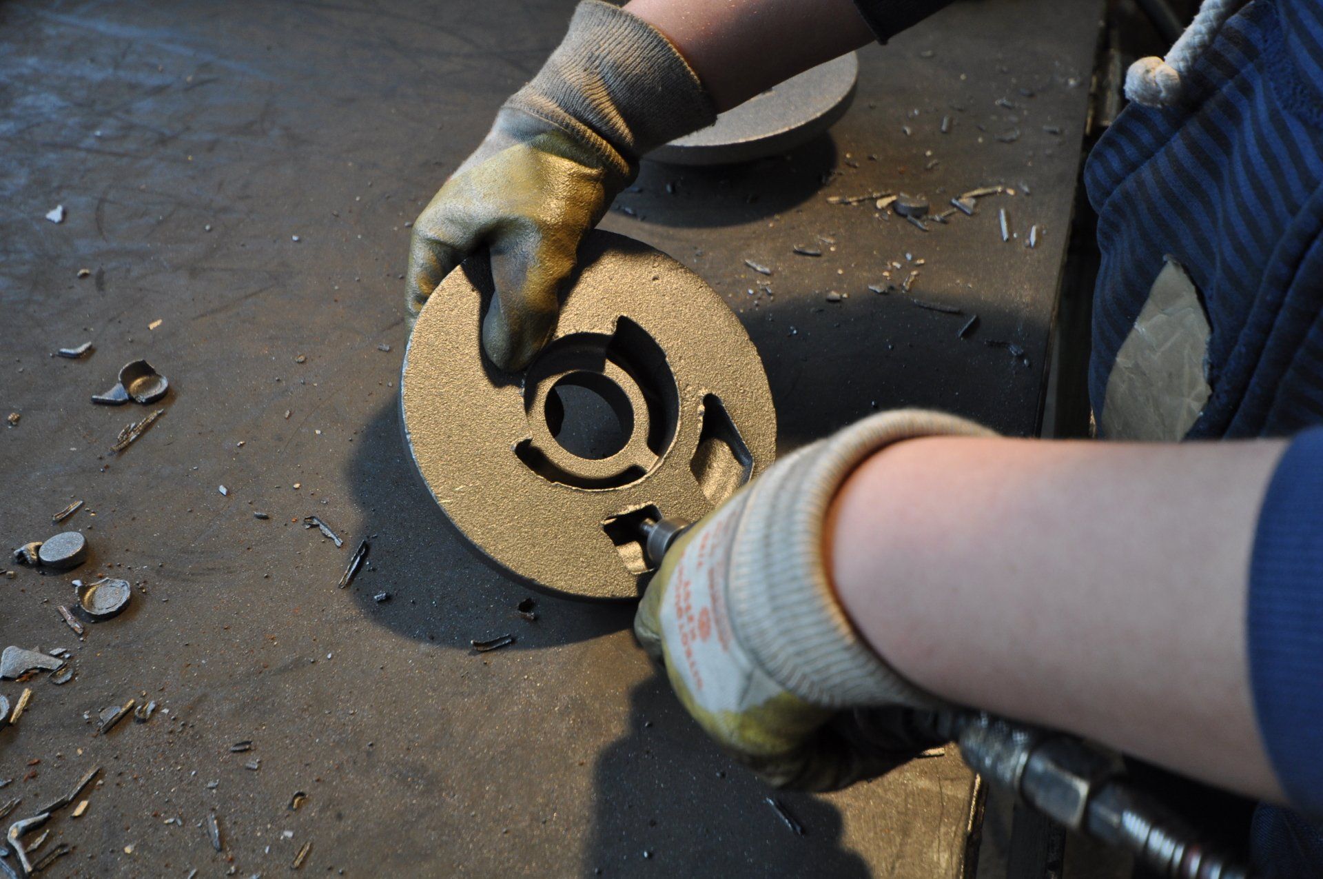 Una persona che indossa guanti sta lavorando su un pezzo di metallo