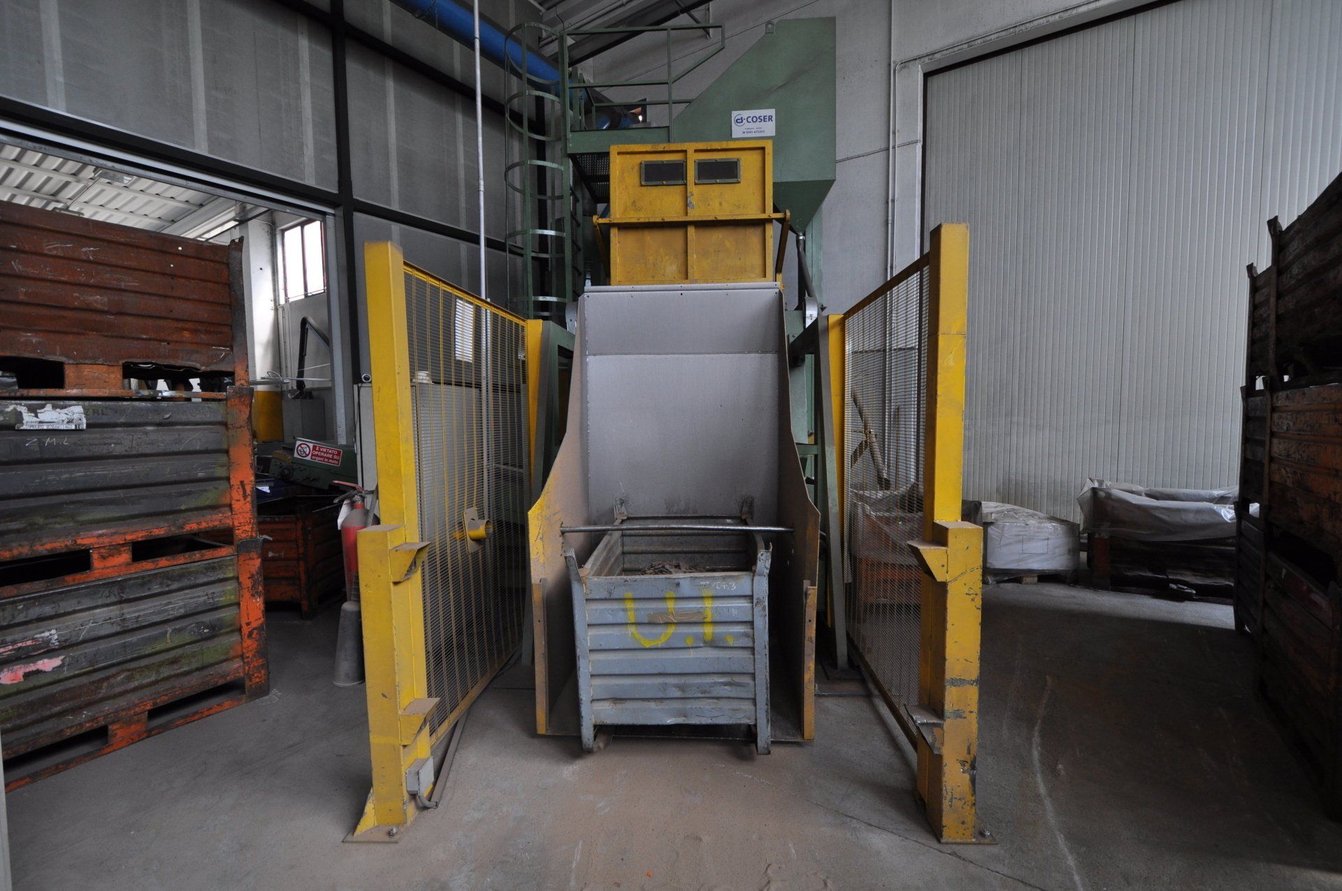Un magazzino con molti pallet di legno e un macchinario.