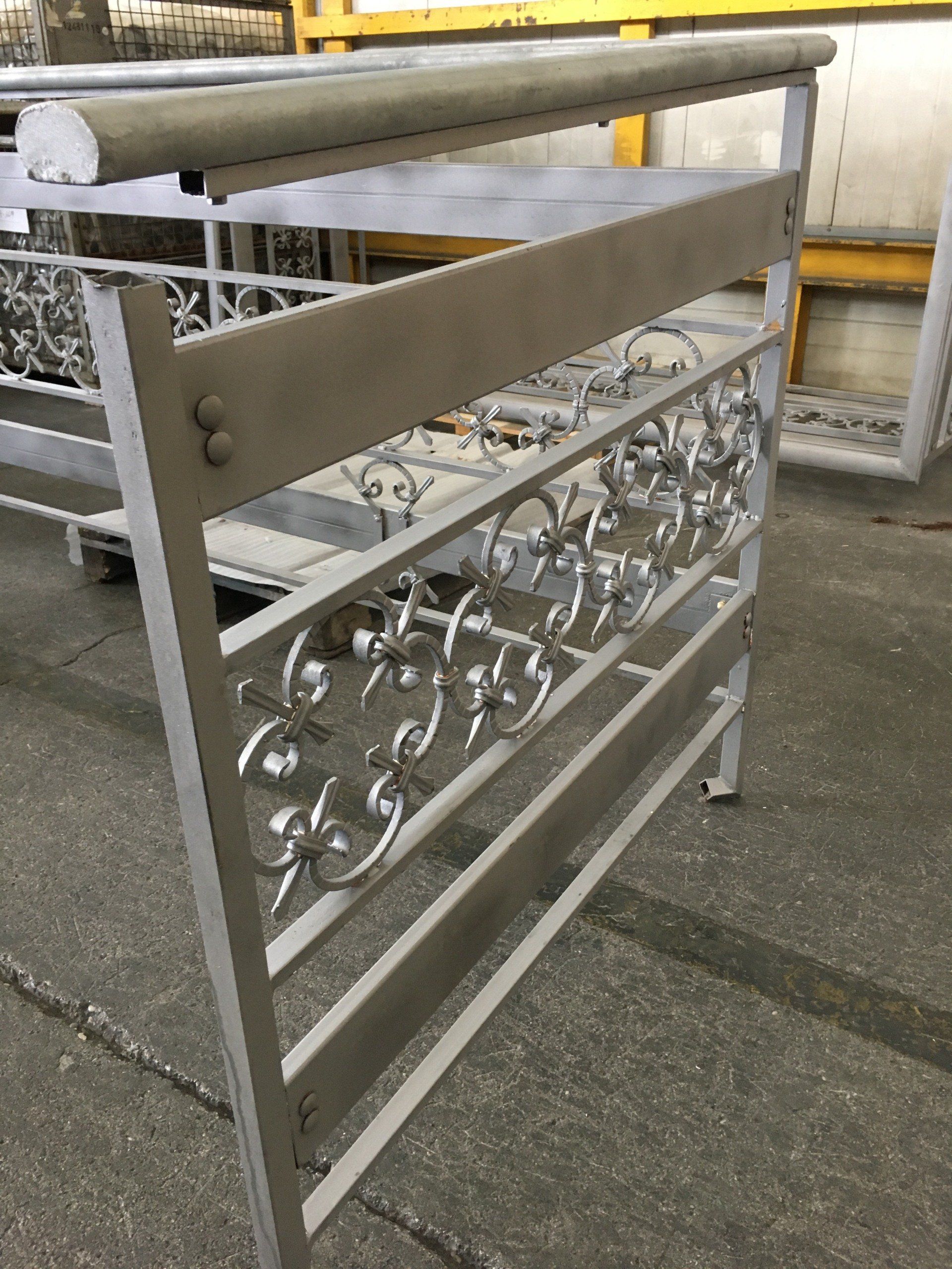 Una ringhiera metallica con un disegno floreale è appoggiata a terra.