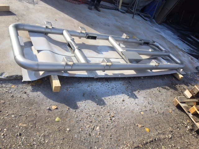 Una struttura metallica è appoggiata a terra accanto a pallet di legno