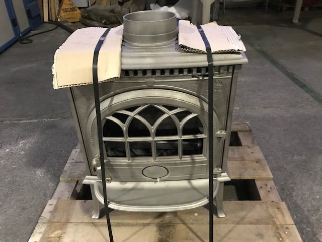 Una stufa a legna è appoggiata su un pallet di legno