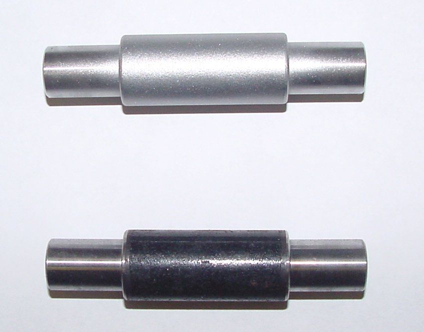 Due tubi metallici sono appoggiati uno accanto all'altro su una superficie bianca.