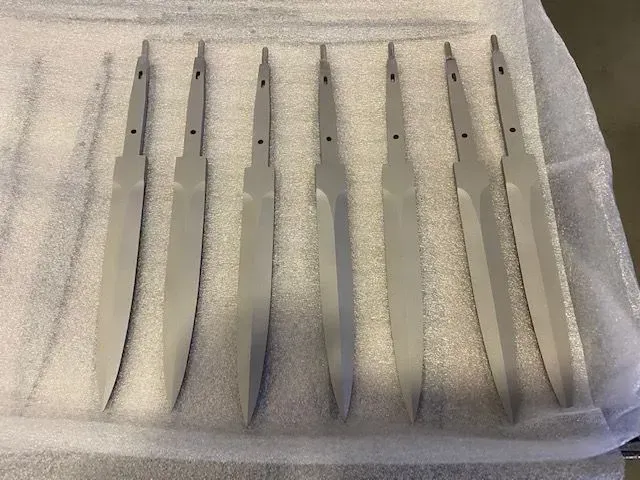 Sei strumenti da scultura con manico bianco, adagiati su un asciugamano di stoffa.