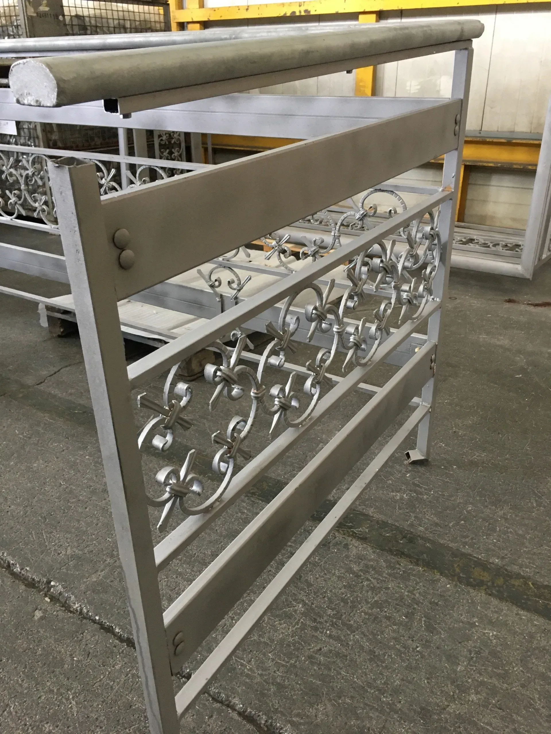 Cancello in metallo con pannelli decorati bianchi e traverse orizzontali accanto a un marciapiede esterno