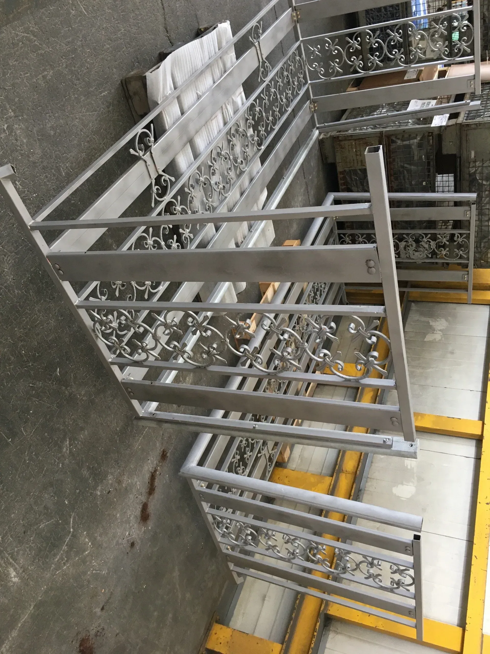Carrelli metallici impilati in un'area di stoccaggio industriale con segnaletica a pavimento gialla.