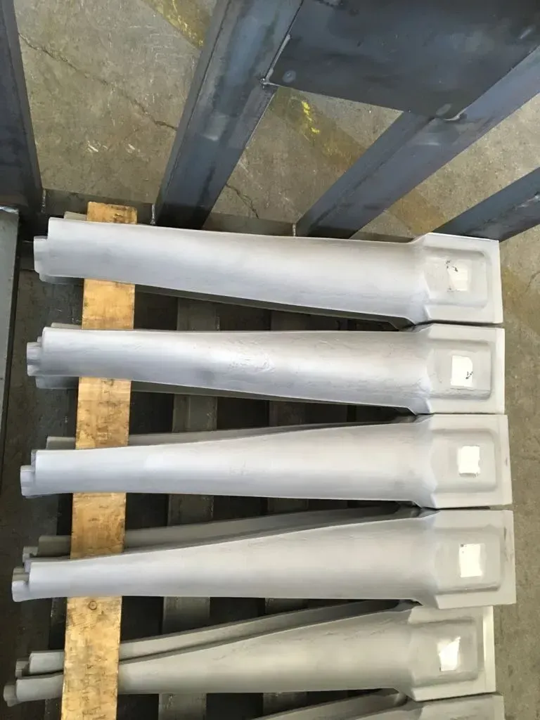 Cinque componenti in plastica grigia impilati su un pallet di legno appoggiato a una scaffalatura industriale in metallo.