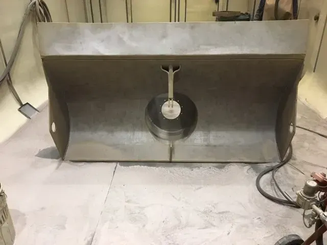 Cartello o cornice espositiva in metallo vuoto con supporto circolare centrale in un ambiente di officina.
