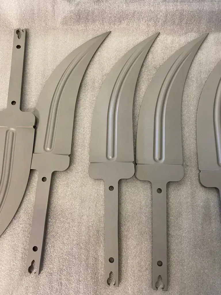 Quattro componenti di coltello in plastica grigia allineate su una superficie di lavoro punteggiata
