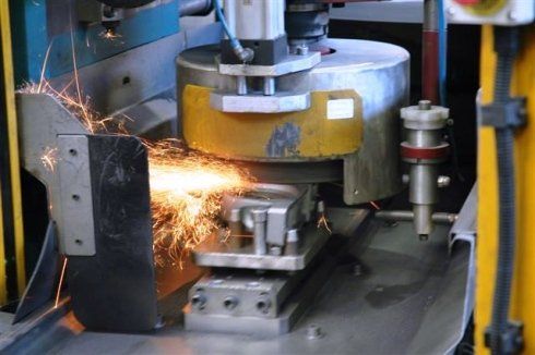 Una macchina sta tagliando un pezzo di metallo da cui escono delle scintille