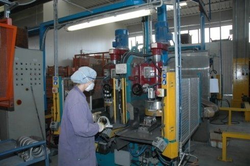 Una donna che indossa una mascherina sta lavorando a un macchinario in una fabbrica.