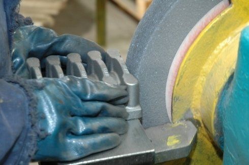 Una persona che indossa guanti blu sta macinando un pezzo di metallo