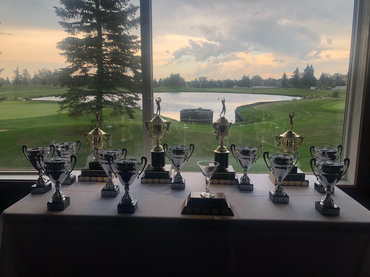 Trophies on a table, with a golf course and lake visible through a window.