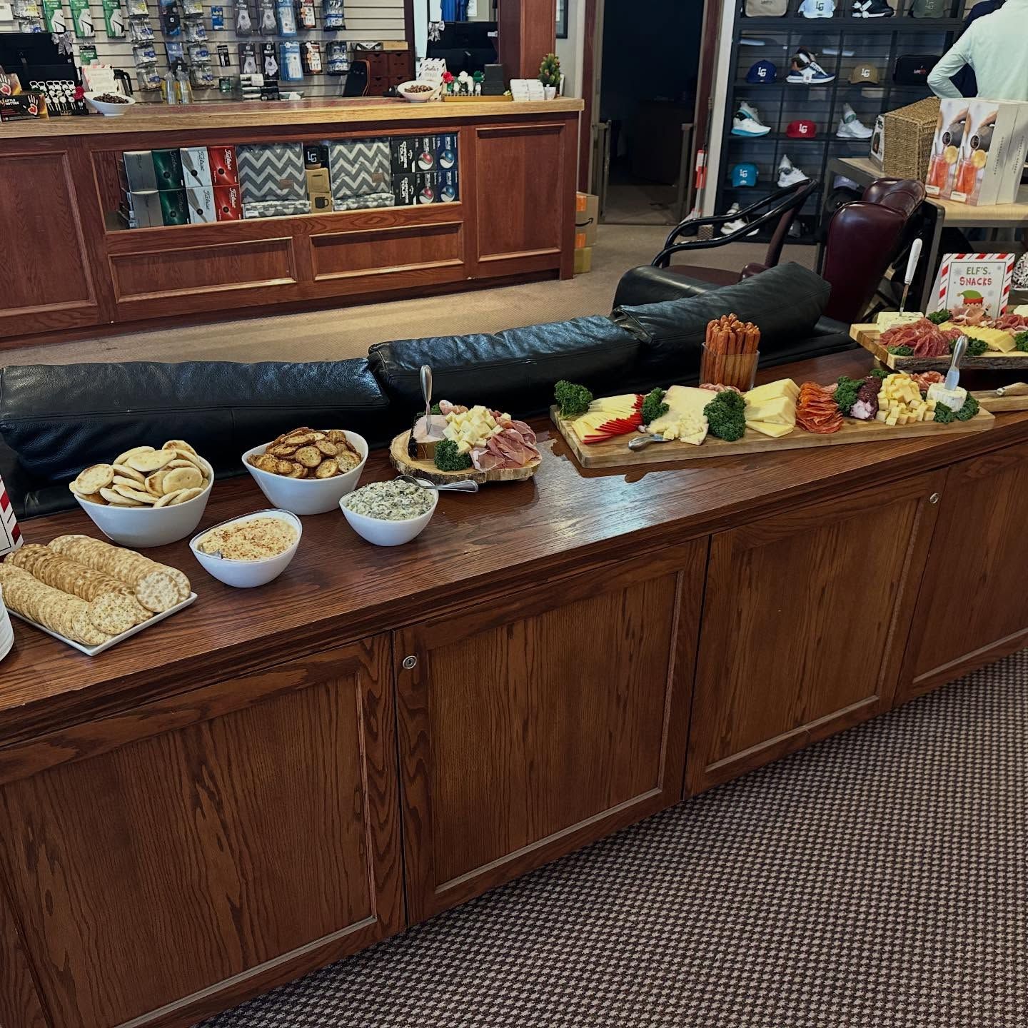 Buffet with snacks: chips, cheese, bread, and dips on a wood counter in a store.