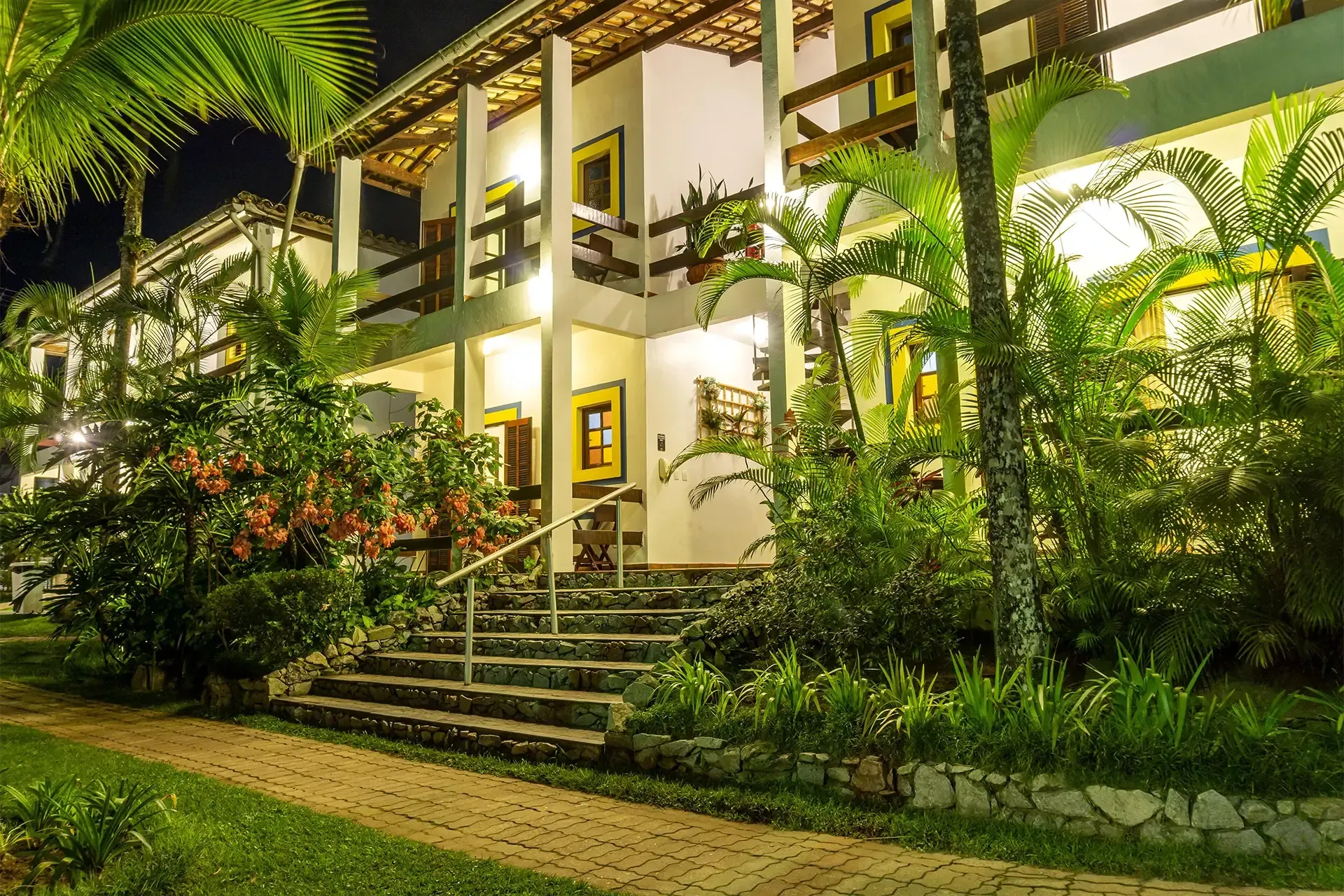 Um grande edifício branco com palmeiras na frente à noite.