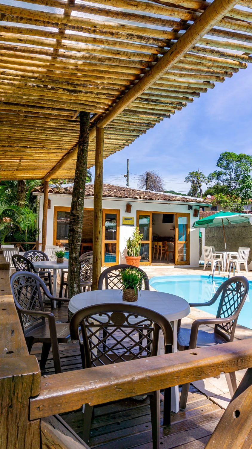 Há mesas e cadeiras em frente a uma piscina.