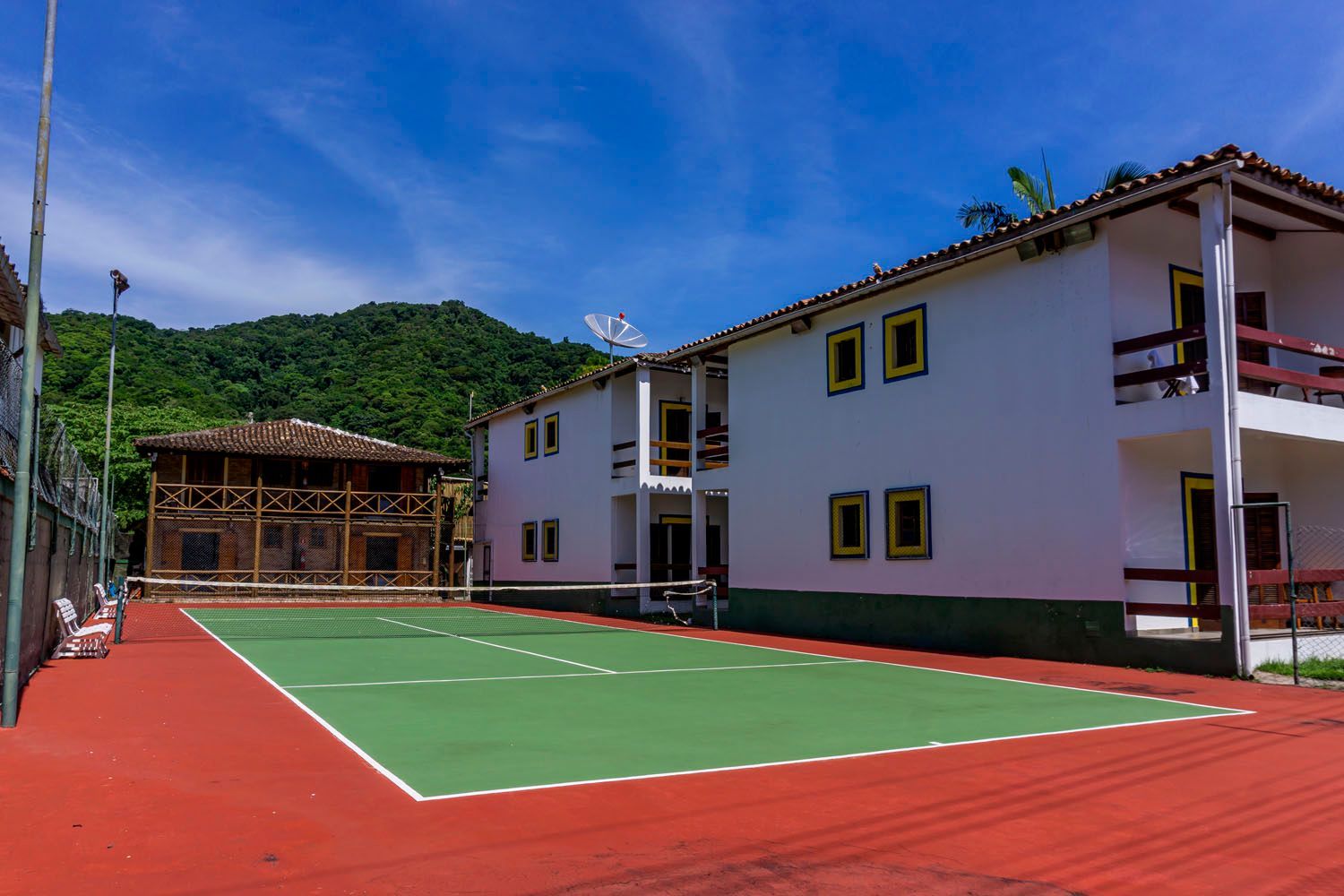 Há uma quadra de tênis em frente a um prédio.