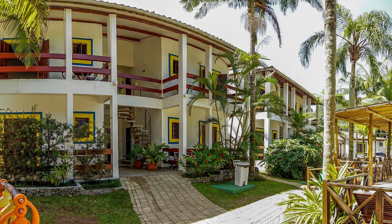 Um grande edifício com muitas janelas e varandas cercado por palmeiras.