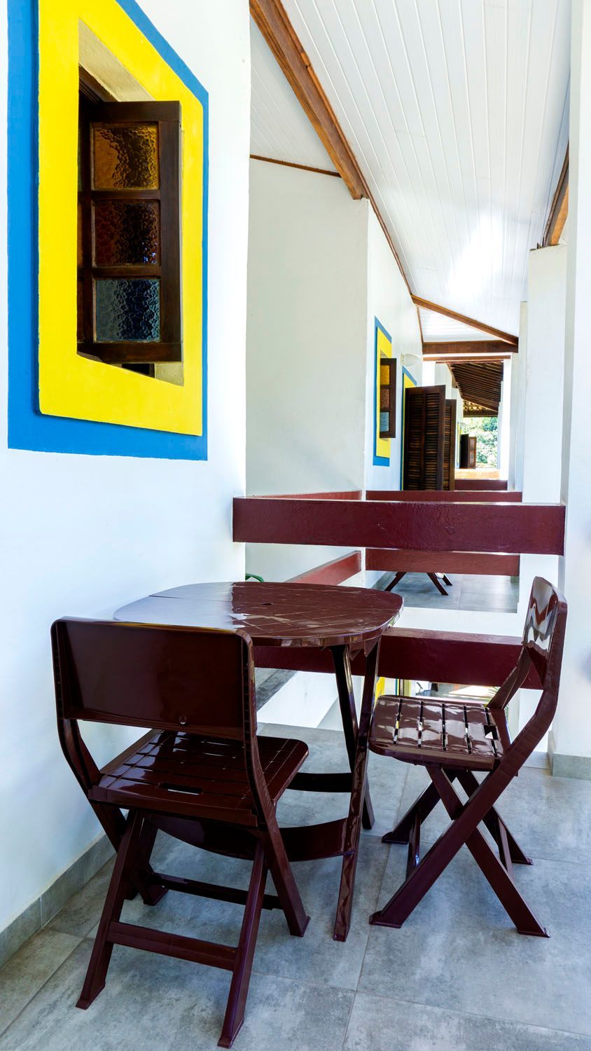 Uma mesa de madeira e cadeiras em um corredor próximo a uma janela.