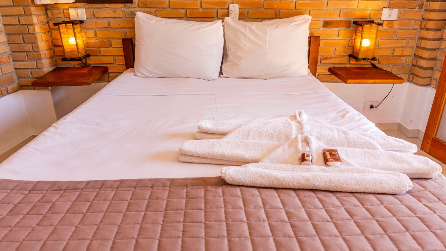 Uma cama com lençóis e travesseiros brancos em um quarto de hotel.