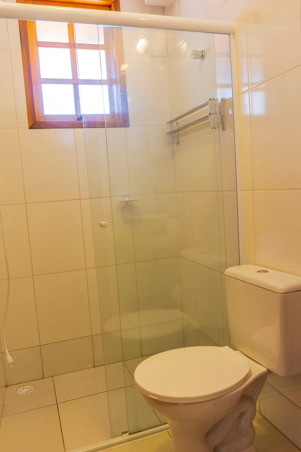 Um banheiro com vaso sanitário e chuveiro com porta de vidro.