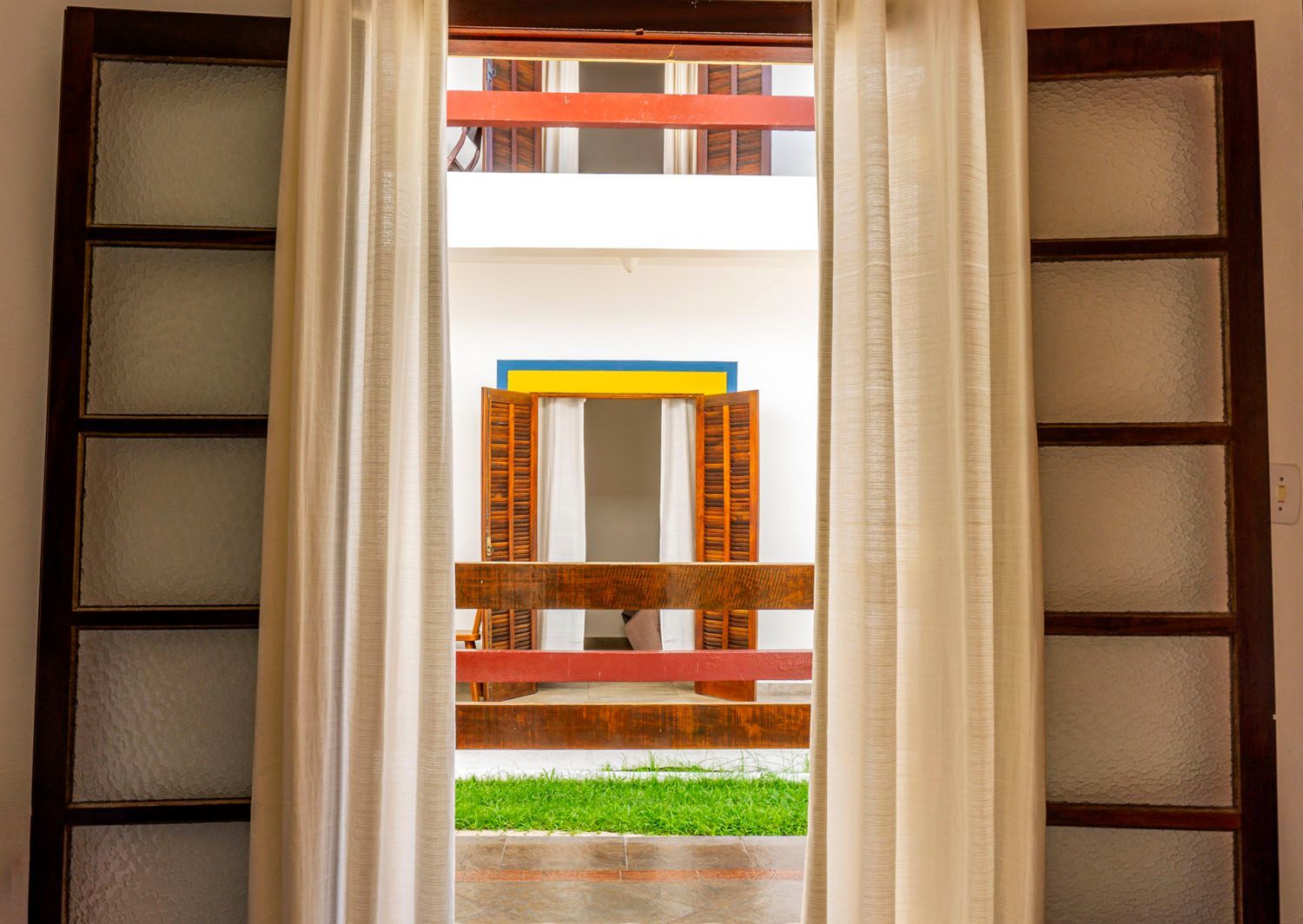 Uma janela com cortinas abertas e vista de um prédio.