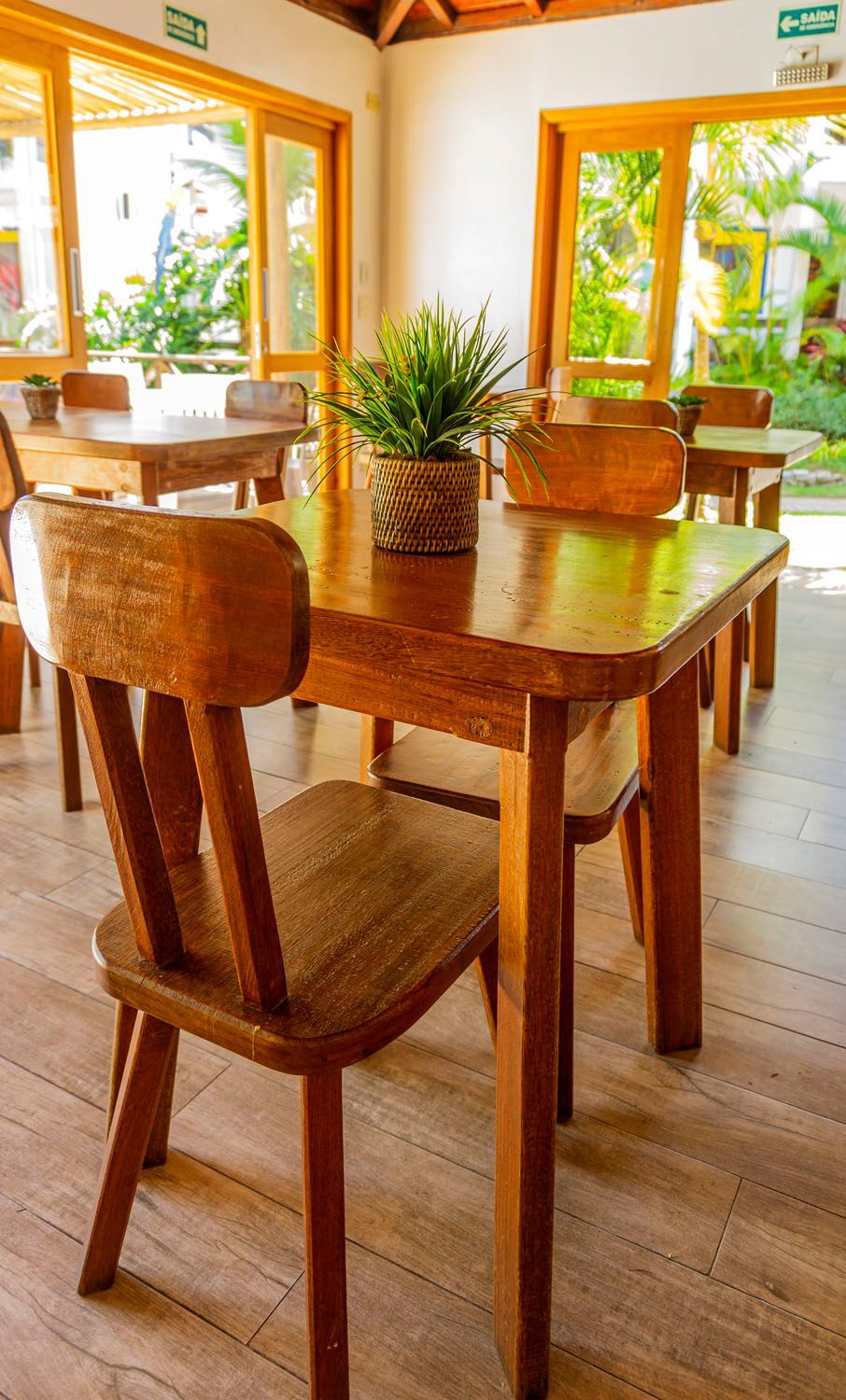 Uma mesa e cadeiras de madeira em um restaurante com um abacaxi na mesa.