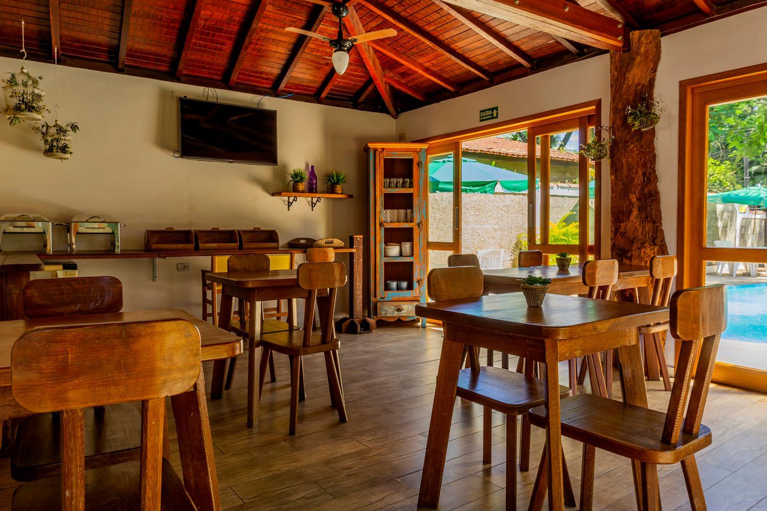 Uma sala de jantar com mesas e cadeiras de madeira e um ventilador de teto.