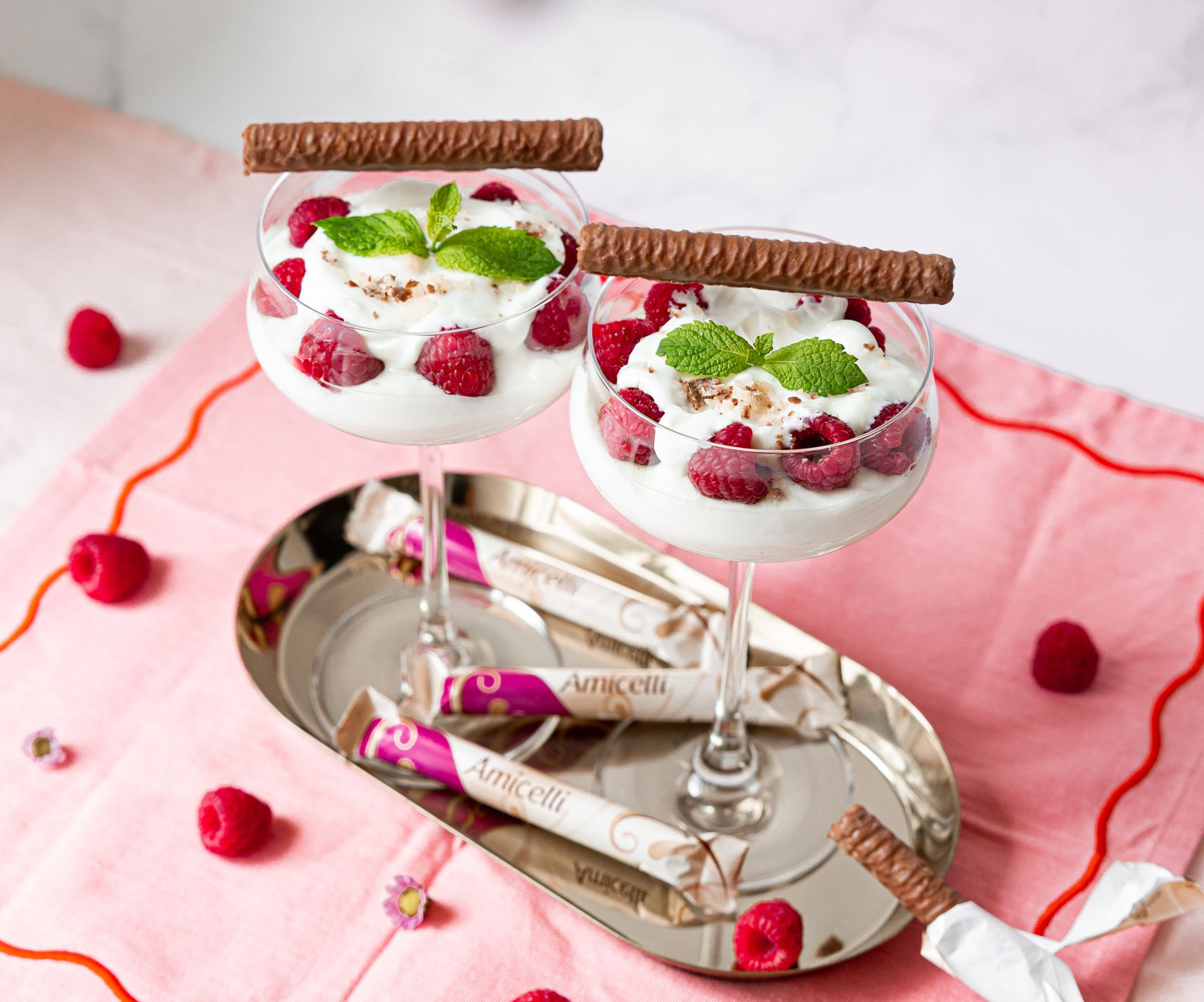 A box of amicielli sits on a table next to a vase of paper flowers