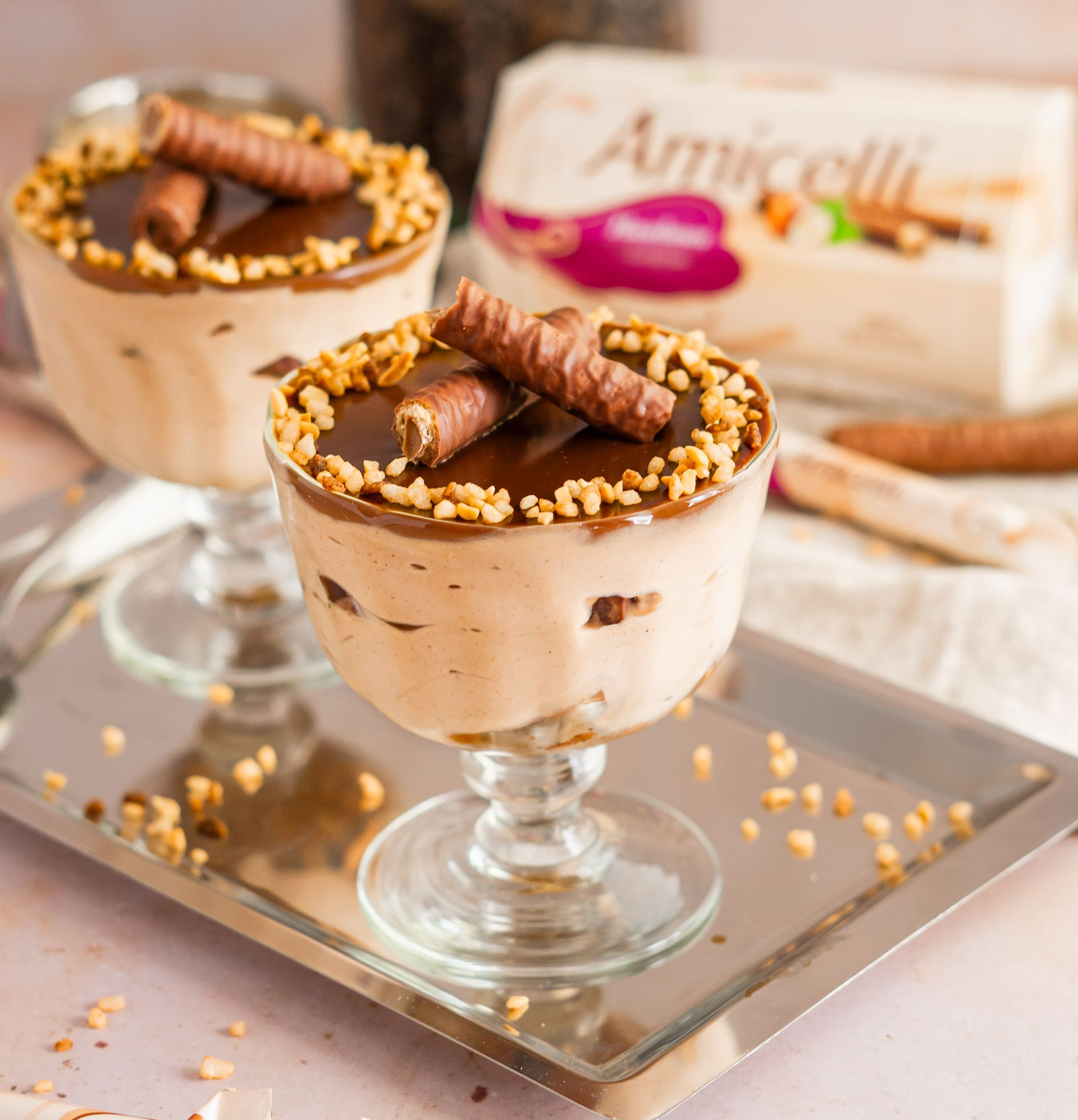 A box of amicielli sits on a table next to a vase of paper flowers