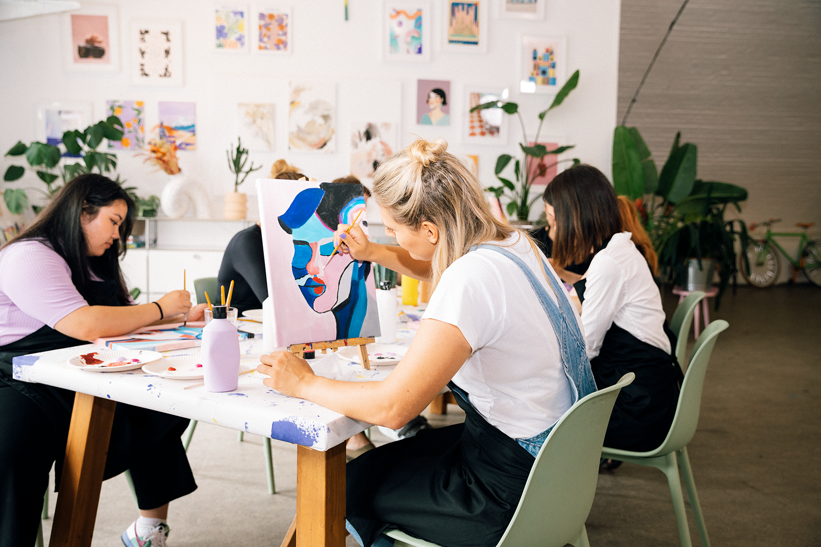 A group of women are sitting at a table painting.