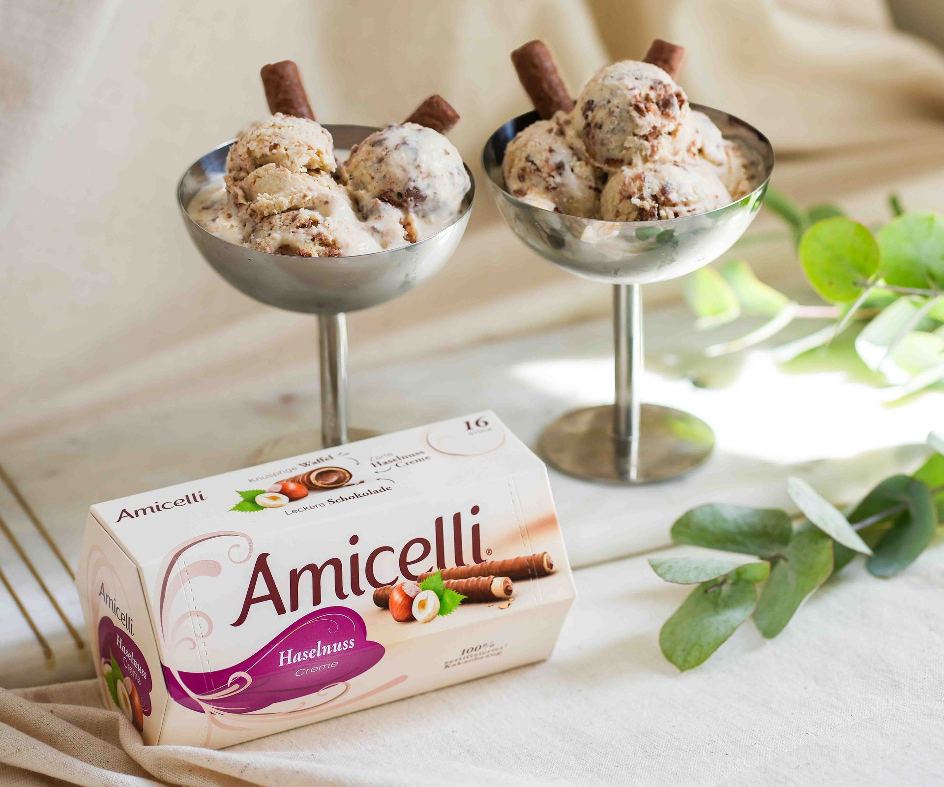 A box of amicielli sits on a table next to a vase of paper flowers