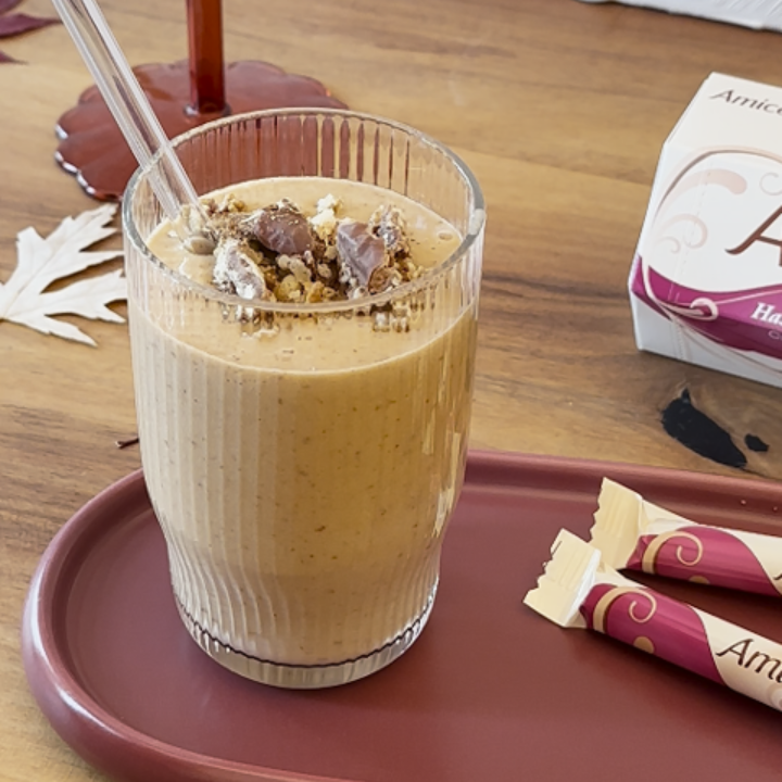 A box of amicielli sits on a table next to a vase of paper flowers
