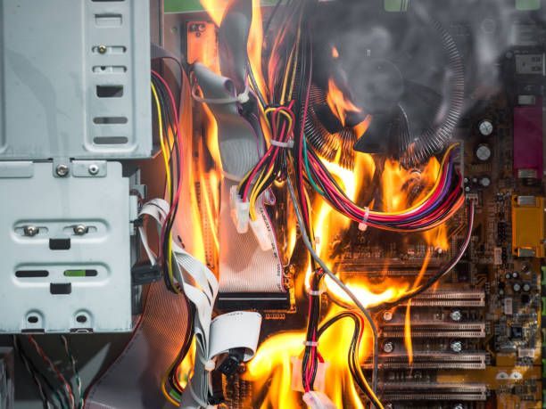 The interior of a computer tower with a motherboard and cables engulfed in bright, active flames.