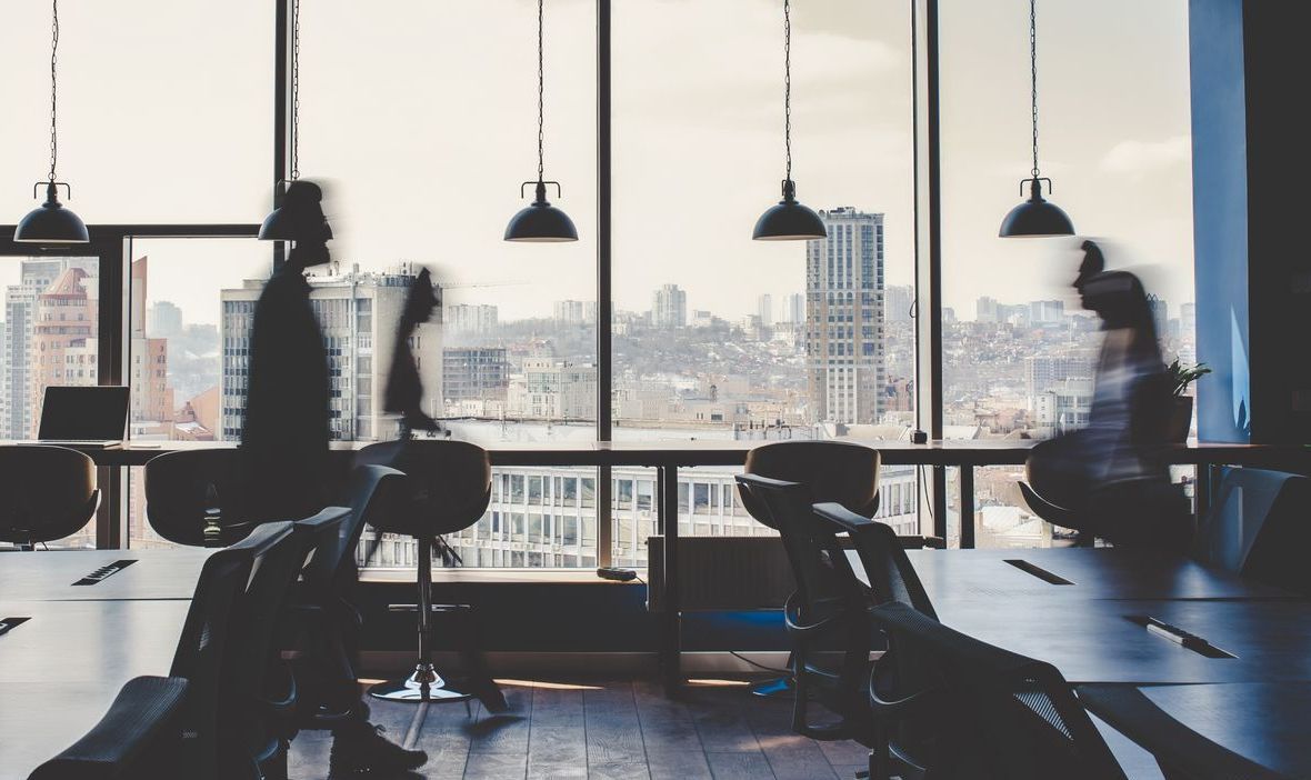 A blurry picture of people sitting at tables in an office.